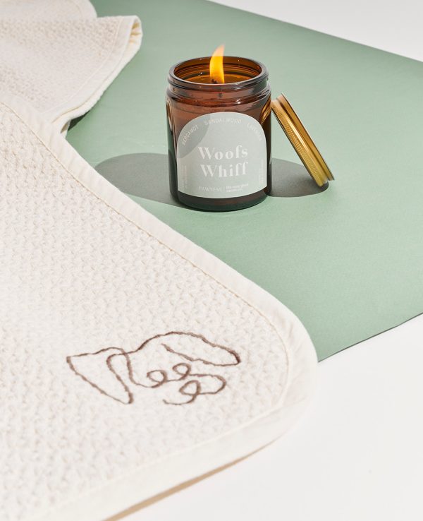 A candle and a towel featuring a dog design.